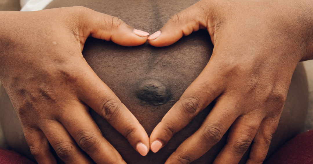 woman holding her belly making a heart with his hands