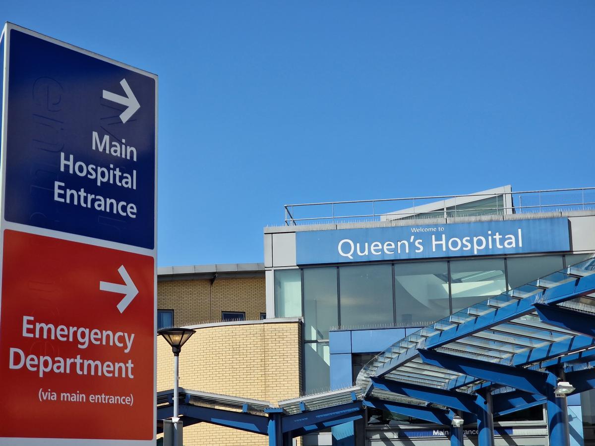 A sign outside Queen's Hospital with directions towards the Emergency Department